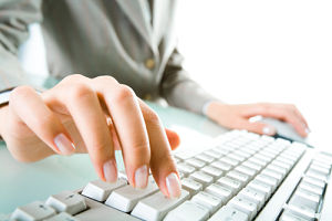 Picture of a female placing her left hand on a computer mouse and her right hand fingers on a keyboard.